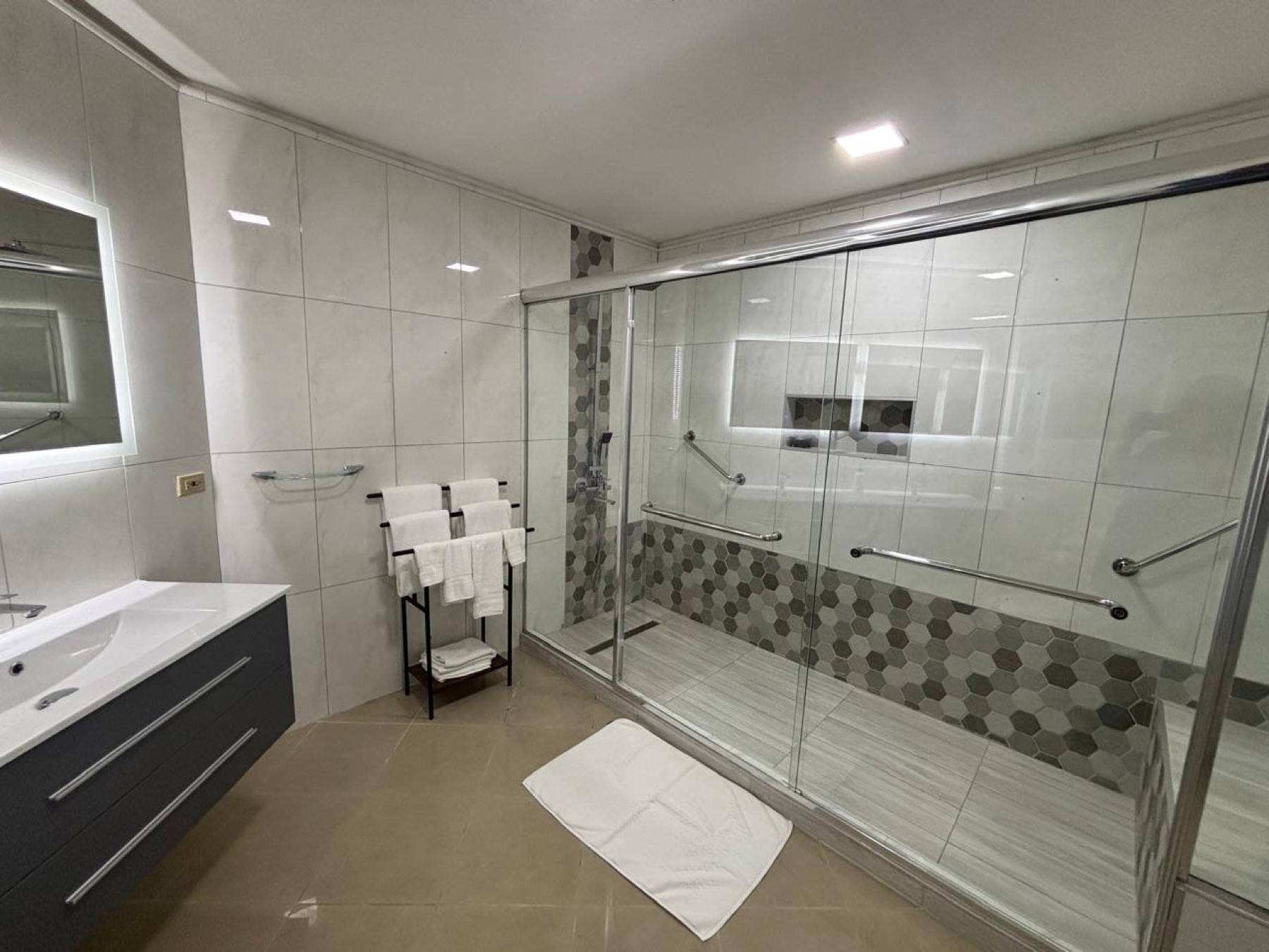 A large bathroom with a glass walk-in shower and patterned tiles